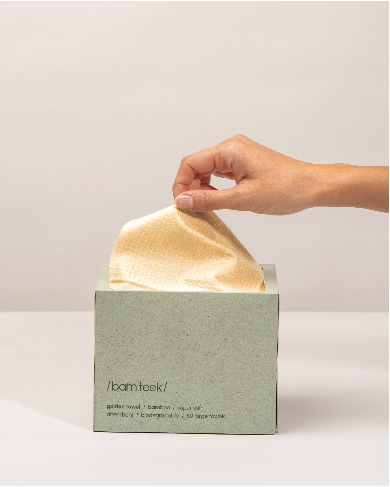 Person reaching for a Golden Towel from a eco-friendly box of 50 large, ultra-soft bamboo disposable towels.